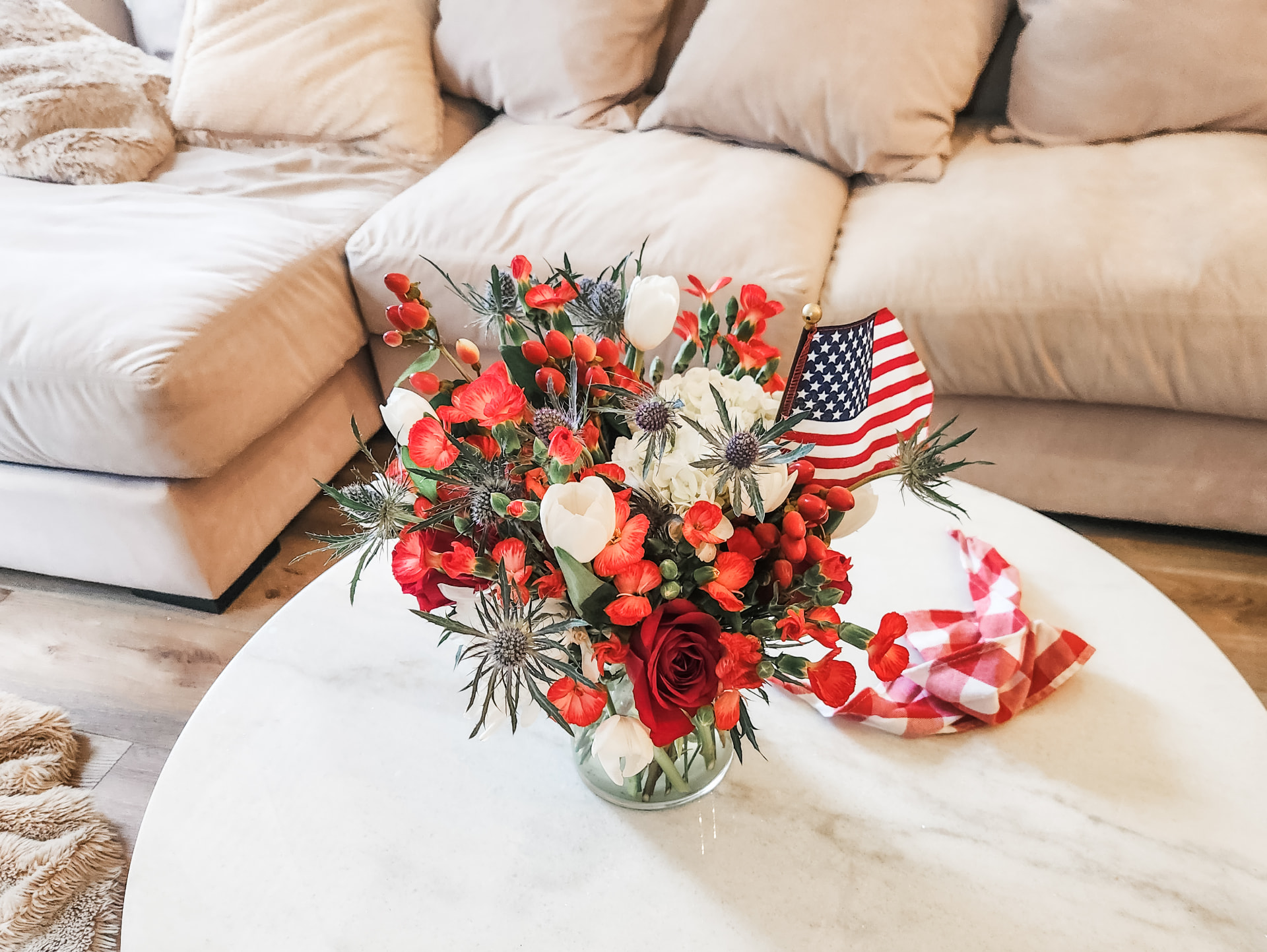 Red rose, white tulip and blue thistle arrangement on a marble coffee table