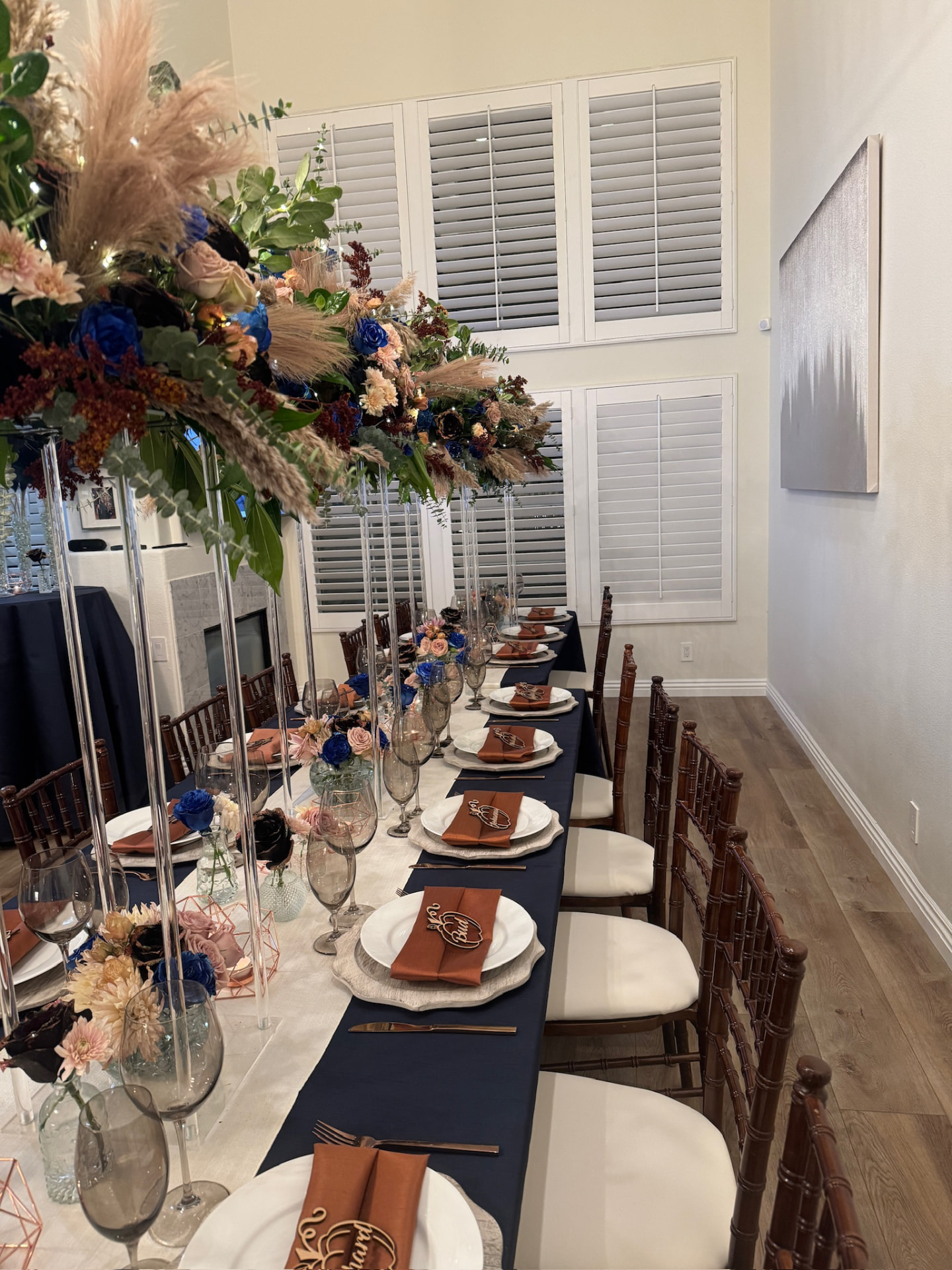 Long navy banquet table with copper napkins and elevated florals down the center