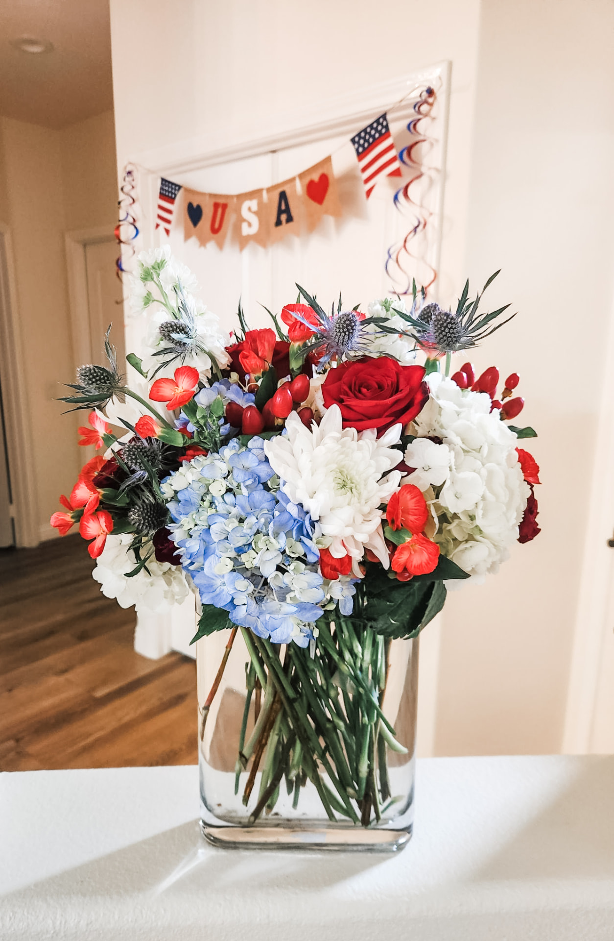 Fourth of July arrangement in red rose, white hydrangea and blue thistle