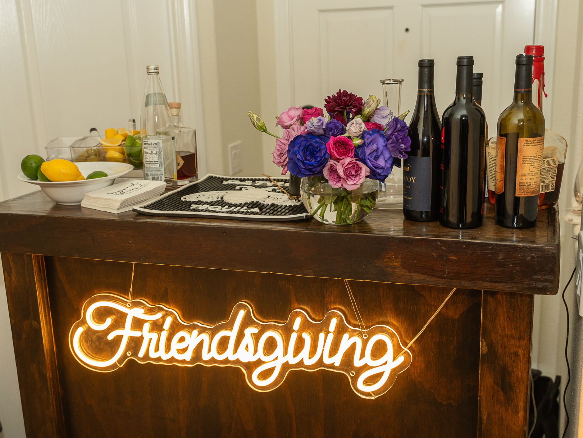 Friendsgiving bar with jewel-toned roses and a neon sign