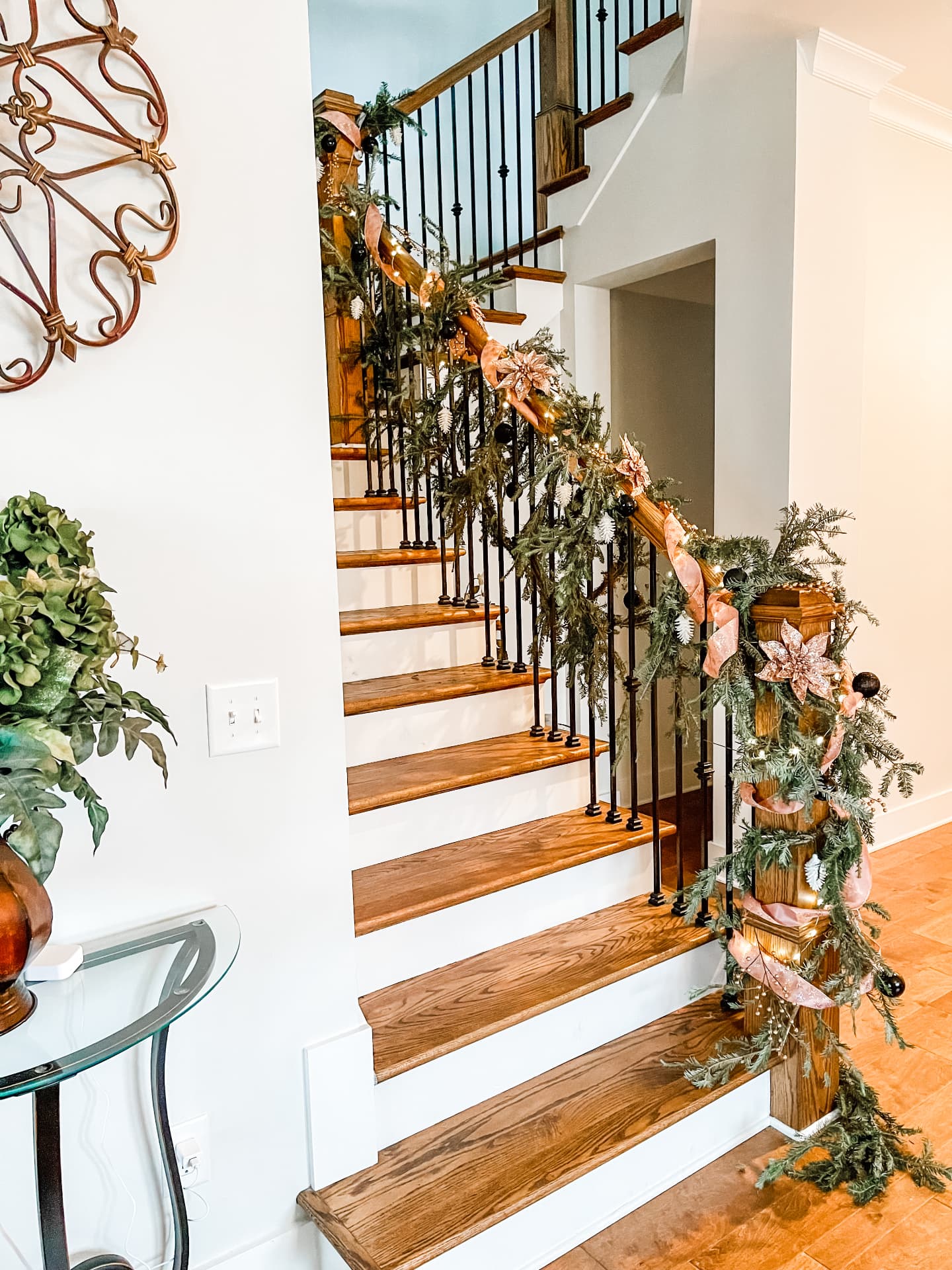 Evergreen staircase garland with blush ribbon and warm light