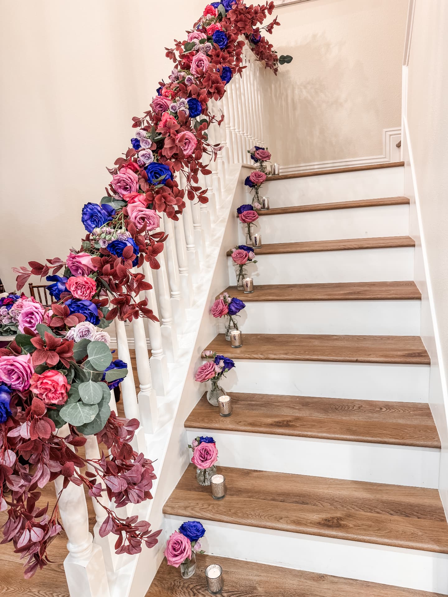 Jewel-toned staircase garland with bud vases and votives on every step