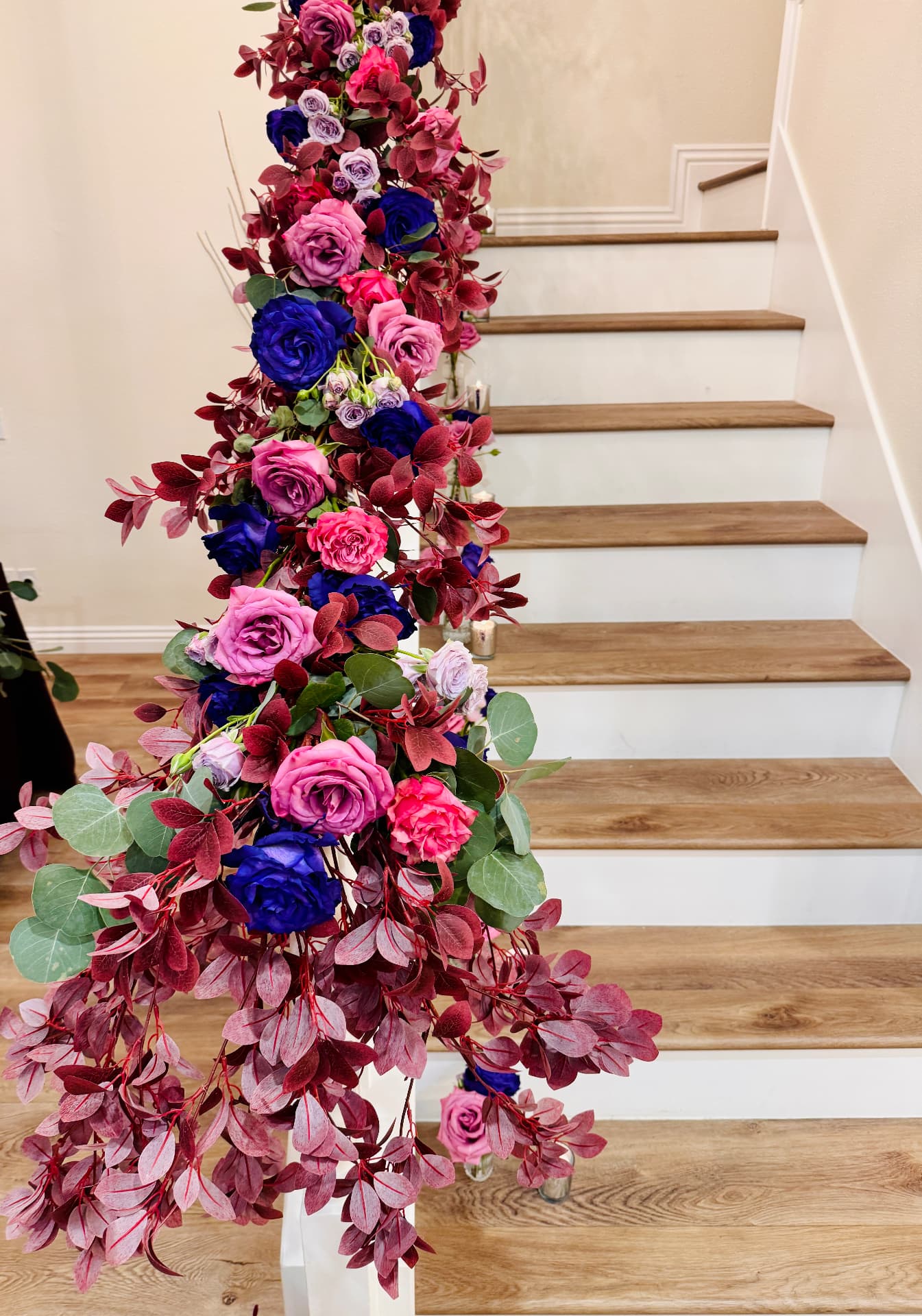 Cascading sapphire and magenta roses in burgundy eucalyptus