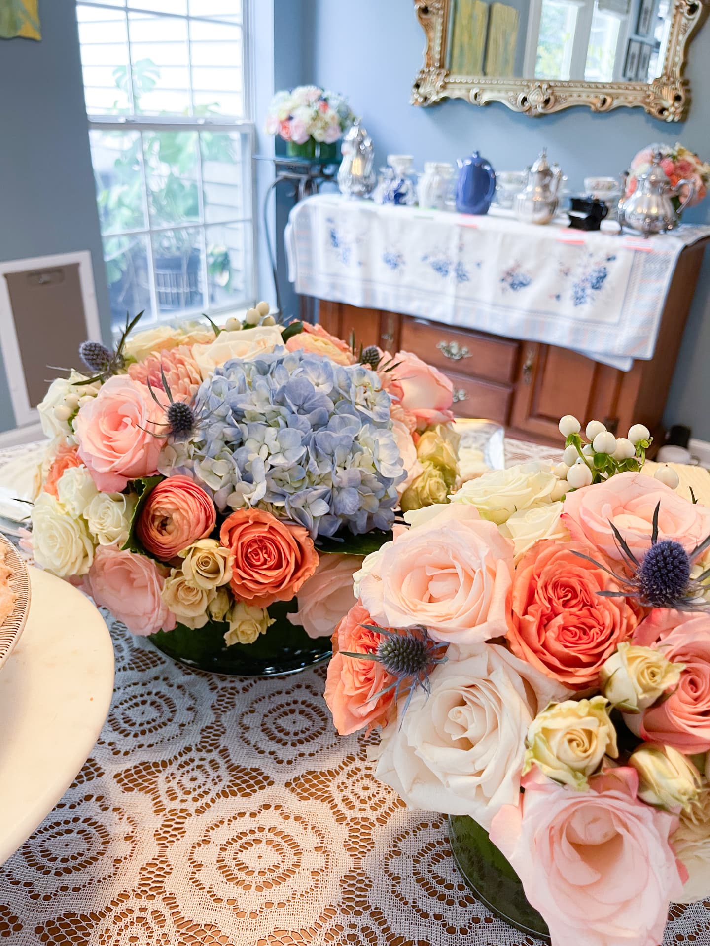 Blue hydrangea and peach rose centerpieces on lace