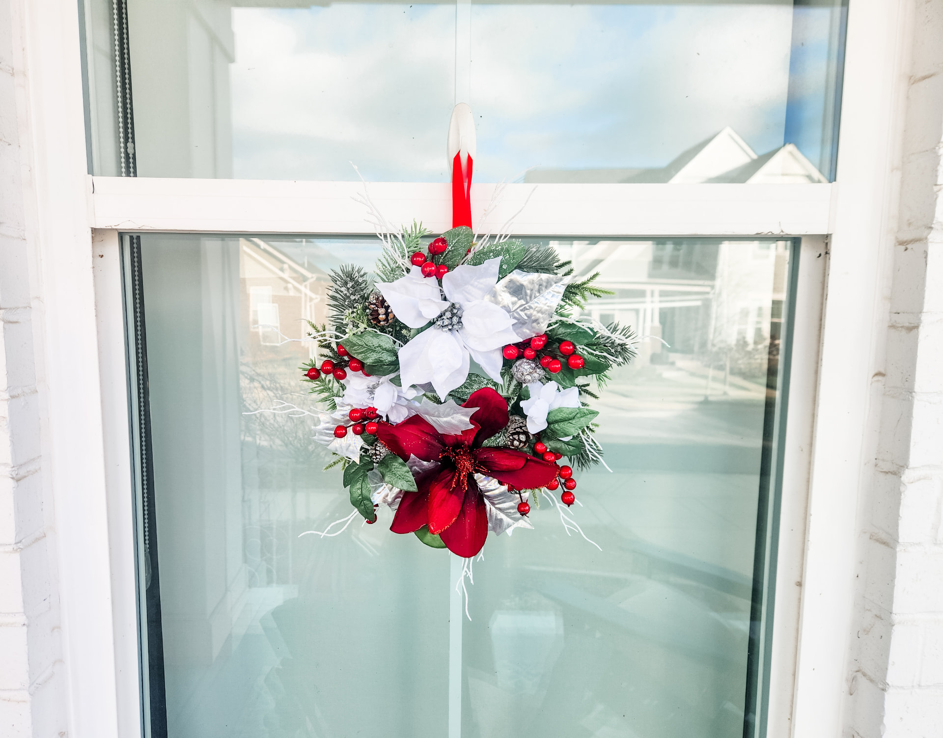 Poinsettia and berry window wreath on red ribbon