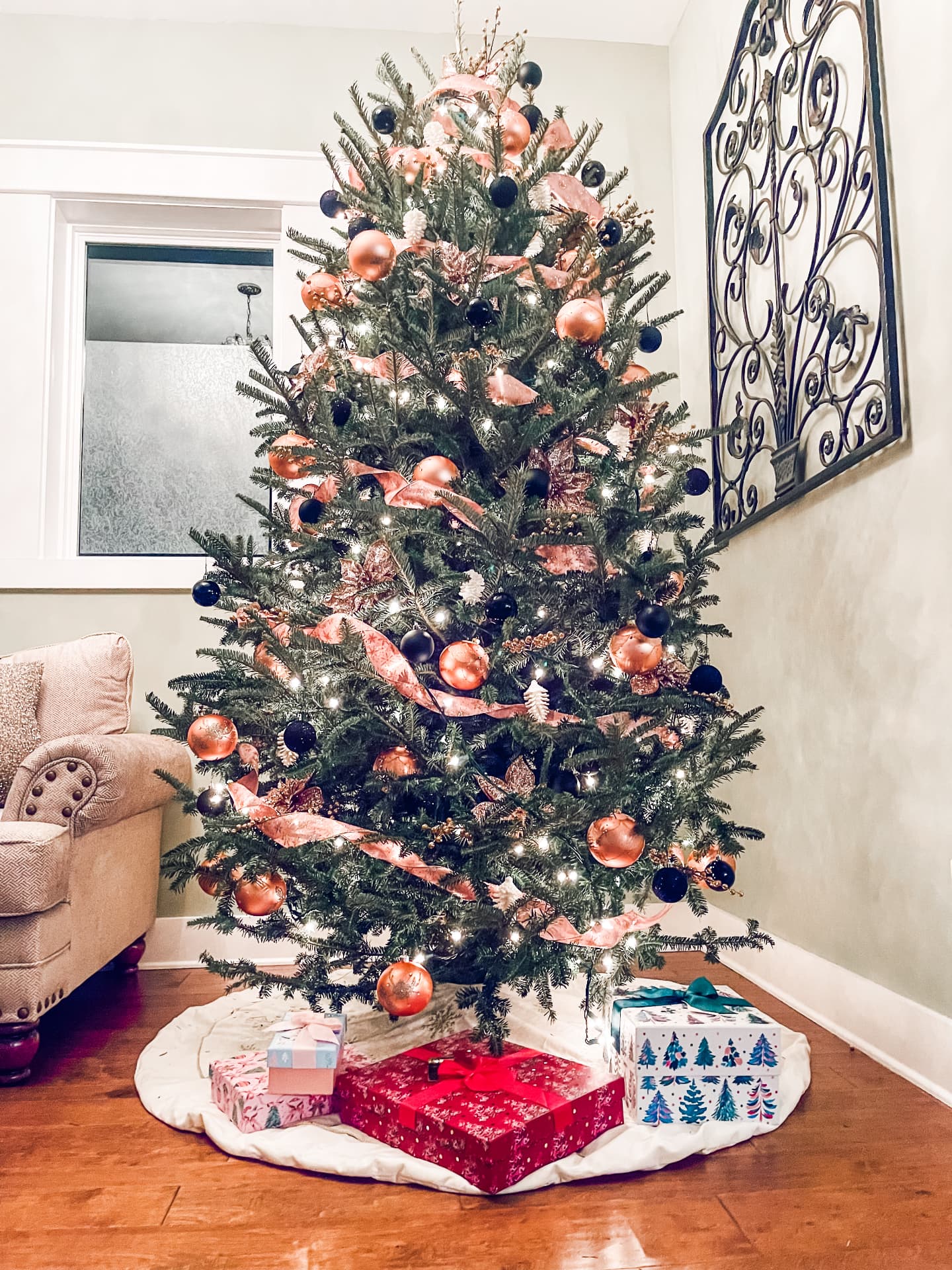 Copper ribbon, blush poinsettia and black ornaments on fresh fir
